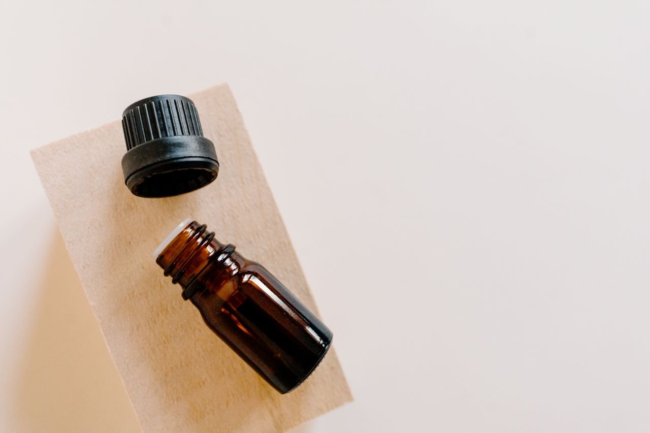 High-angle shot of an open brown essential oil bottle with its cap off on a wooden surface.